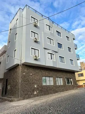 a tall white building on top of a brick building at Nos Cantin in Mindelo
