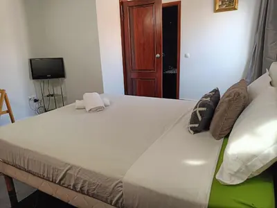 a bedroom with a large white bed and a television at Casa Miami in Tarrafal