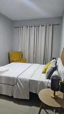 a bedroom with a white bed and a yellow chair at Palmarejo Cozy Retreat in Praia