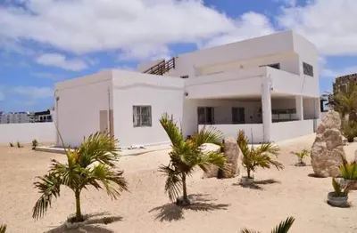 a white house with palm trees in front of it at Casa Estoril, Boa Vista in Sal Rei