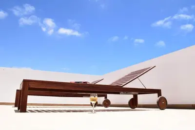a wooden bench with a glass of wine next to it at Casa Estoril, Boa Vista in Sal Rei