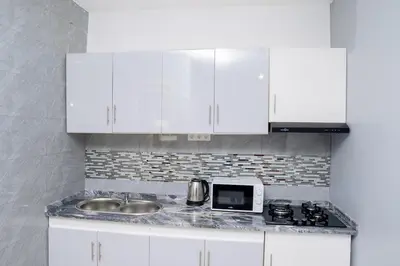 a kitchen with white cabinets and a sink and a microwave at J Martins Apart T11 Tarrafal in Tarrafal