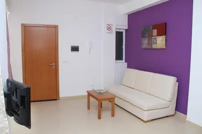 a living room with a white couch and a tv at Delfim Apartamentos in Praia