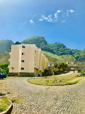 a street with a building and mountains in the background at Conforto de um Lar in Ponta do Sol