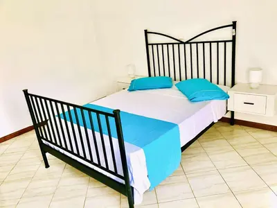 a bedroom with a large bed with blue pillows at Conforto de um Lar in Ponta do Sol