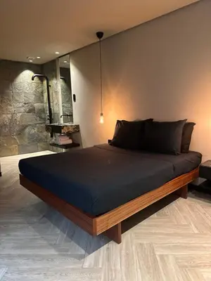 a large bed in a room with a stone wall at Santiago Apartment in Mindelo