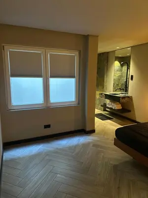 a bedroom with two windows and a wooden floor at Santiago Apartment in Mindelo