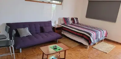 a living room with a purple couch and a tv at Djarfogo house in São Filipe