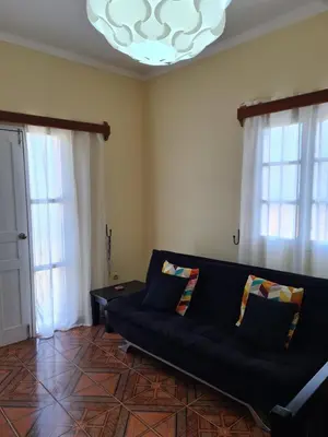 a living room with a black couch and a chandelier at Djarfogo house in São Filipe