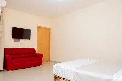 a bedroom with a red couch and a tv at J Martins ApartHotel in Tarrafal