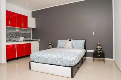 a bedroom with a bed and a red kitchen at J Martins ApartHotel in Tarrafal