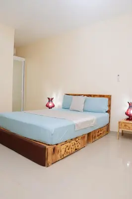 a bed with a wooden frame in a room at J Martins ApartHotel in Tarrafal