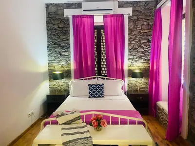 a bedroom with pink curtains and a large bed at Techas City Center Luxe Suites in Praia