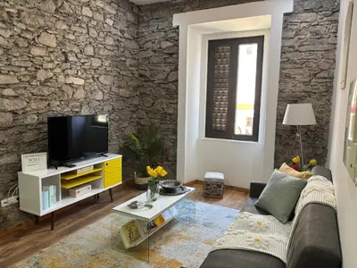 a living room with a couch and a tv at Techas City Center Luxe Suites in Praia
