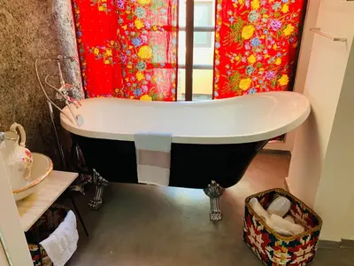 a bath tub in a bathroom with a red shower curtain at Techas City Center Luxe Suites in Praia