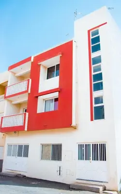 a red and white building with white windows at Morabeza & Mar in Porto Novo