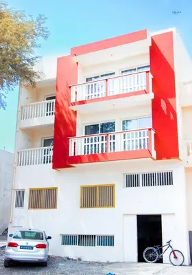 a white and red building with a car parked in front at Morabeza & Mar in Porto Novo