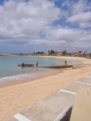two people standing on a beach with a boat in the water at Coral Reef in Santa Maria