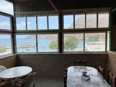a table and chairs in a room with windows at Mar Azul Tarrafal APARTMENT in Tarrafal