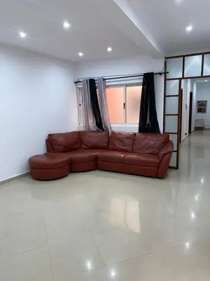 a brown leather couch in a living room with a window at Mar Azul Tarrafal APARTMENT in Tarrafal