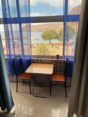 a table and chairs in a room with a large window at Mar Azul Tarrafal APARTMENT in Tarrafal