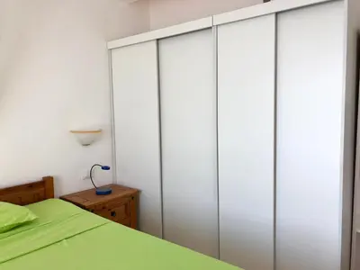 a bedroom with white closet doors and a green bed at Beachapartment fully serviced in Sal Rei