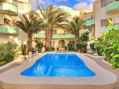 a pool in front of a building with palm trees at Capo Verde Club - Ca Francesca in Santa Maria