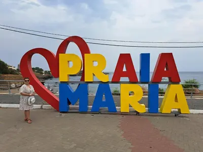 a woman standing in front of a sign that reads peruvian man at Cap Ouest Praia in Praia