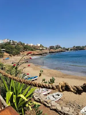 a beach with umbrellas and boats on the sand at Cap Ouest Praia in Praia
