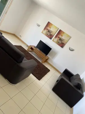 a living room with a black couch and a table at condomínio vila verde Pepper, Cactus T0,T1,T2 in Santa Maria