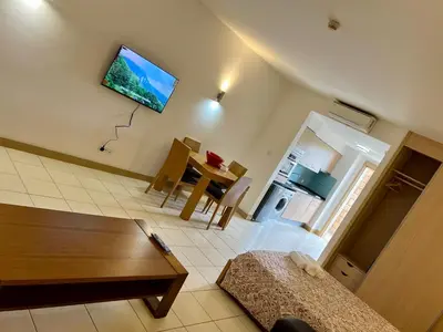 a living room with a table and a tv on the wall at condomínio vila verde Pepper, Cactus T0,T1,T2 in Santa Maria