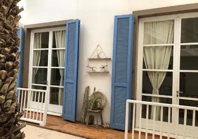 a house with blue shutters on a porch at Appartamenti Praia Estoril, Sal Rei, Boa Vista in Sal Rei