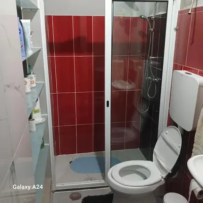 a bathroom with a toilet and a shower with red tiles at Casa brunosky in Mindelo