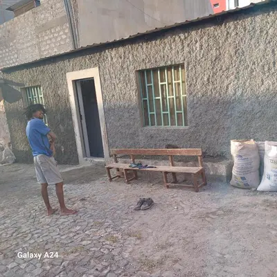 a man standing next to a bench and a building at Casa brunosky in Mindelo