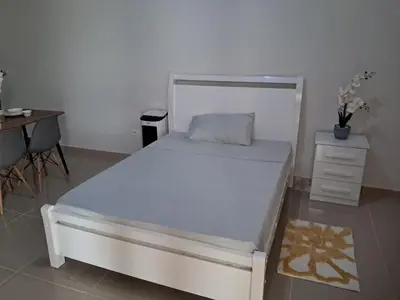 a bedroom with a bed and a table and a desk at T0 Cabral Next Door in Sal Rei