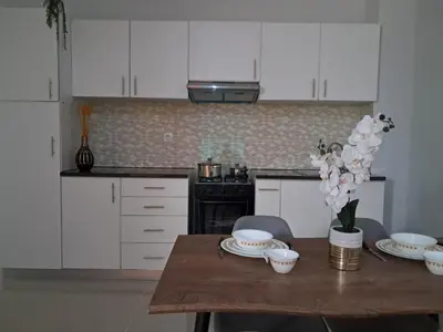 a kitchen with white cabinets and a wooden table with flowers at T0 Cabral Next Door in Sal Rei