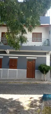 a blue and white building with two brown doors at Holiday's House in Praia