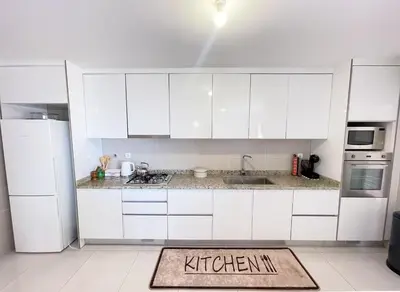 a kitchen with white cabinets and a kitchen rug on the floor at Marel Bliss Apartments T2 Camila in Mindelo