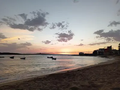 a sunset on the beach with boats in the water at Onda do Mar in Sal Rei