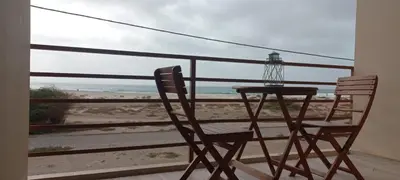 a table and chair on a balcony with a view of the beach at Onda do Mar in Sal Rei