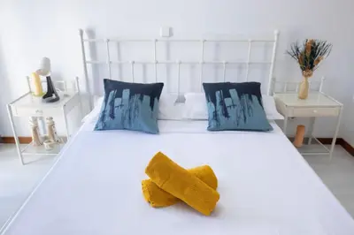a white bed with a yellow bow tie on it at Marel Bliss Apartments T2 Lorena in Mindelo