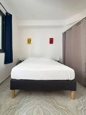 a bedroom with a bed with white sheets and blue curtains at Spacious 3-bdr apartment - Palmarejo Grande - LCGR in Praia