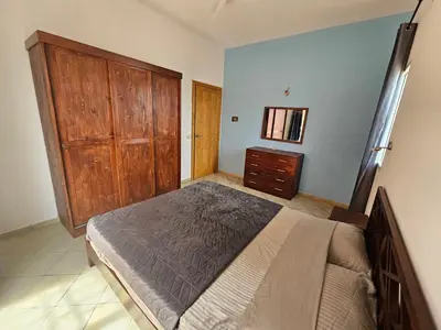 a bedroom with a bed and a wooden cabinet at Bouganville Holiday Apartment in Santa Maria