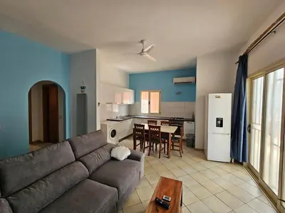 a living room with a gray couch and a kitchen at Bouganville Holiday Apartment in Santa Maria