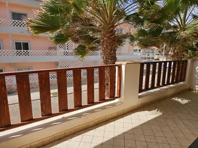 a wooden fence with a palm tree in front of a building at Bouganville Holiday Apartment in Santa Maria
