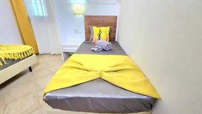 a small bed with a yellow blanket on it at T&C No Stress apartment in Santa Maria