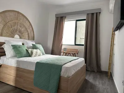 a bedroom with a bed with a green blanket on it at Cozy Flat in Praia