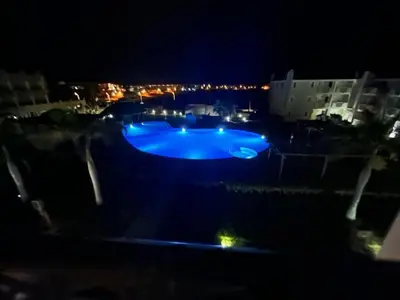 a large blue swimming pool at night with lights at Brisa Tropical in Santa Maria