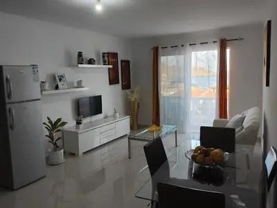 a white living room with a table and a refrigerator at Ocean view Apartment 2 in Cidade Velha