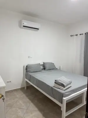 a bed in a room with a white wall at Casa Cucuia in Praia